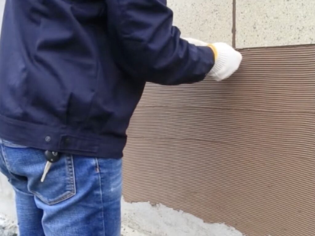 Trabajador aplicando revestimiento ligero de piedra flexible en una pared curva